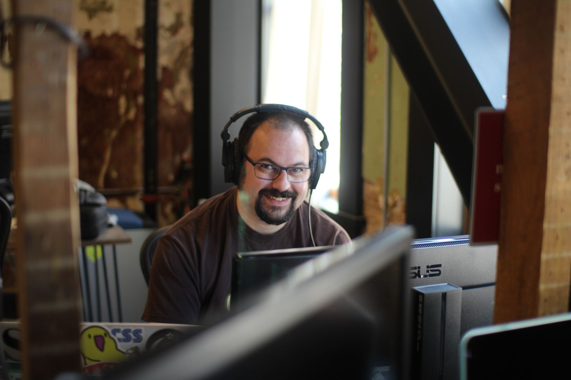 Scott at his desk, wearing headphones and smiling.